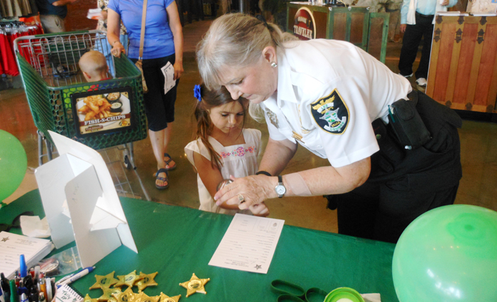 Child fingerprinting a person and a child at a table with a green tablecloth