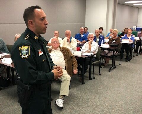 cropped-citizens_academy_2.jpg a person in uniform talking to an audience